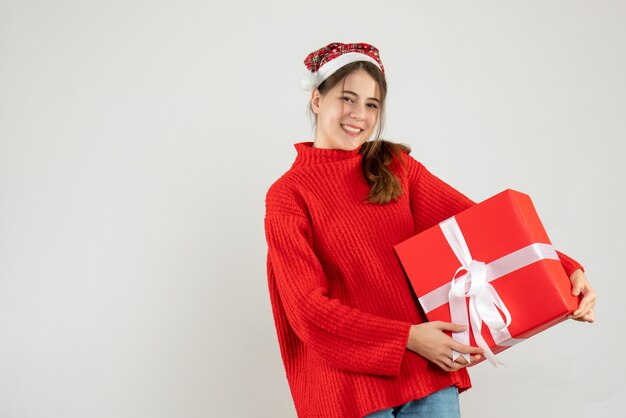 happy girl with santa hat holding her xmas gift on white