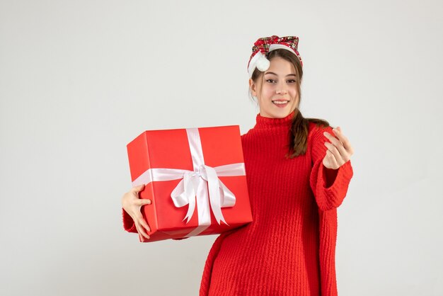 happy girl with santa hat holding present standing on white