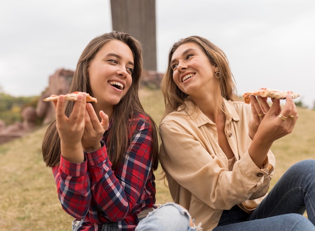 Happy girls eating pizza slices outdoors