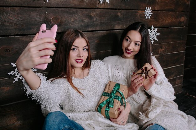 Счастливые девушки с рождественские подарки, принимая фотографии