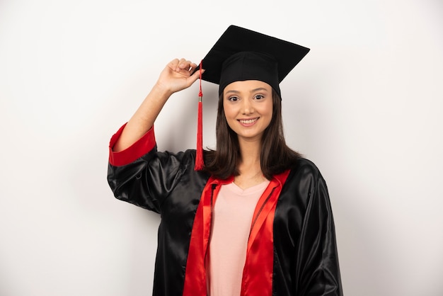 Happy graduate student in gown posing on white background.