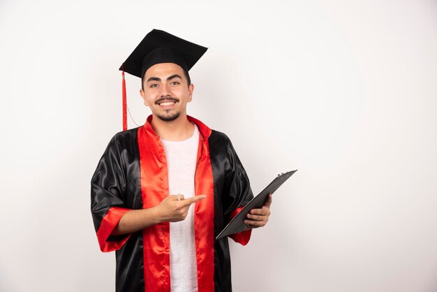 Happy graduate student pointing at his diploma on white.