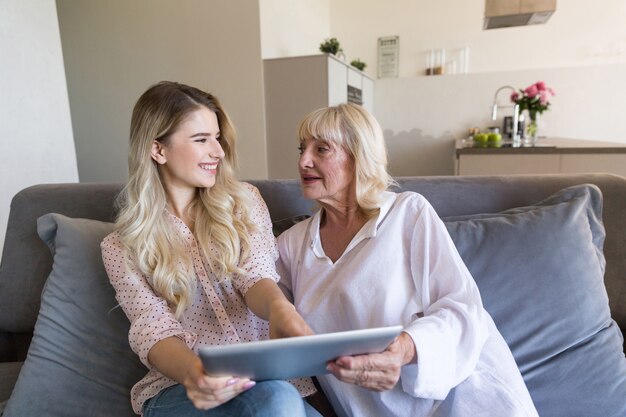 Free photo happy granddaughter and her grandmother using tablet computer