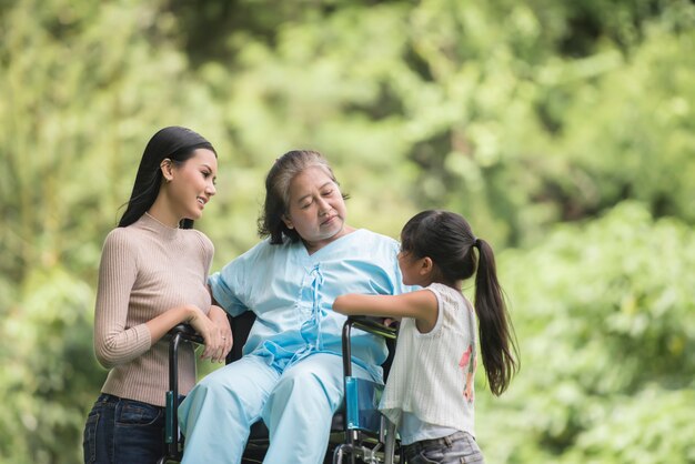 Happy grandmother in wheelchair with her daughter and grandchild in a park, Happy life Happy time.