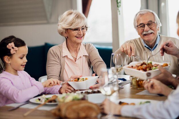 ダイニングテーブルで家族と一緒に昼食をとっている幸せな祖父母