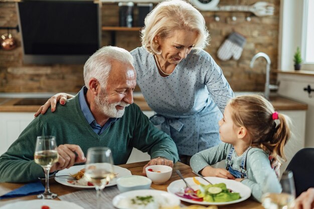 행복한 조부모와 손녀가 식당에서 점심을 먹으면서 의사소통을 합니다.