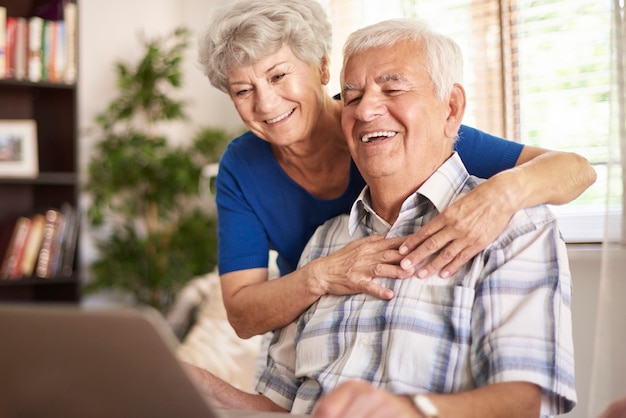 Happy grandparents using their digital laptop
