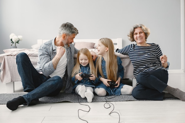 Foto gratuita nonni felici con due nipoti. famiglia che gioca ai videogiochi. seduto per terra.