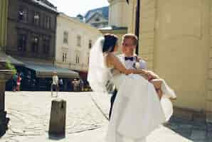 Foto gratuita sposo felice portando la sposa in braccio