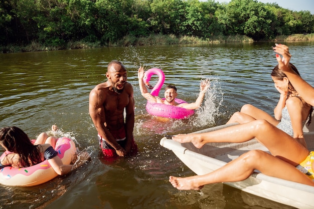笑ったり川で泳いだりしながら楽しんでいる友達の幸せなグループ