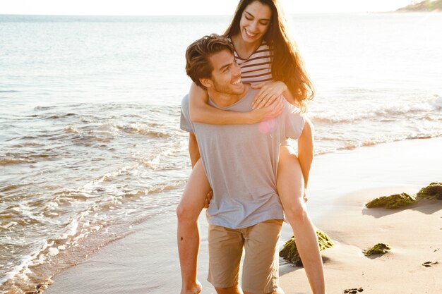 Happy guy carrying girlfriend at the shoreline