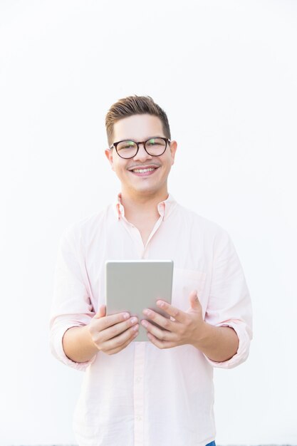 Happy guy in eyeglasses holding tablet