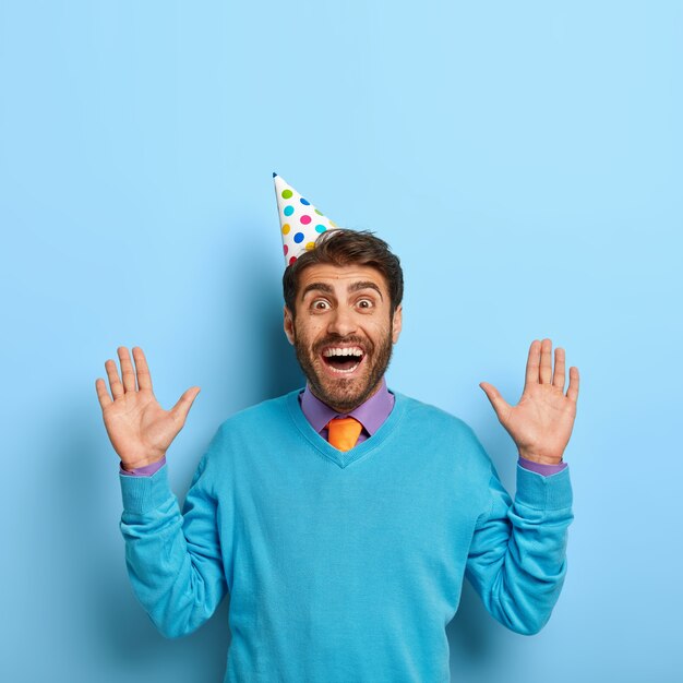 Happy guy with birthday hat posing in blue sweater