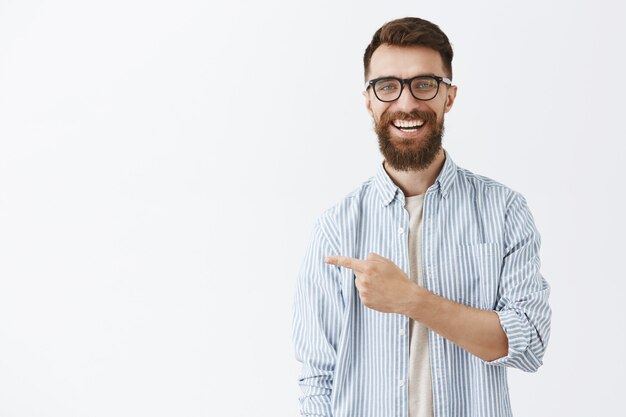 白い壁に向かってポーズをとって幸せなハンサムなひげを生やした男