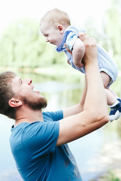 Happy handsome dad, father holding baby boy in blue clothes