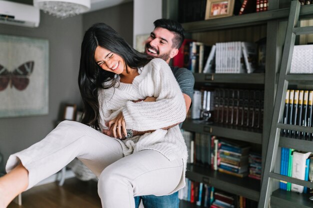 Happy handsome man carrying her girlfriend at home