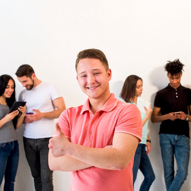 Happy handsome man standing with his friends gesturing thumbup over white background