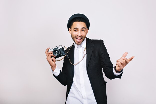 Happy handsome young man in suit, hat having fun with camera. Fashionable look, modern photographer, tourist, weekends, leisure, travelling, expressing positive emotions.