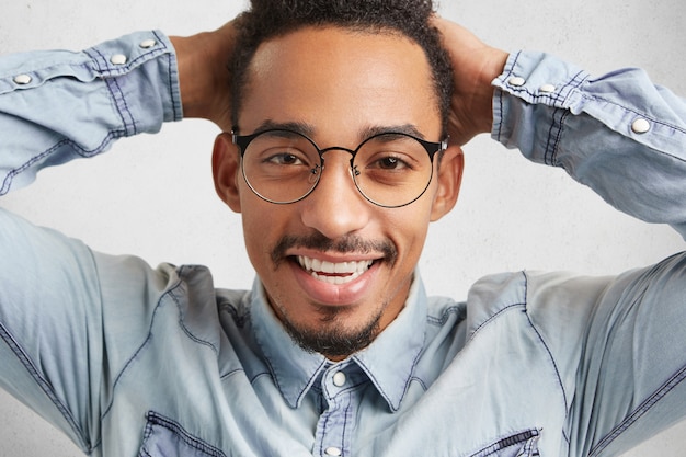Happy hipster guy in big round spectacles feels relaxed