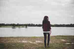 Foto gratuita donna felice hipster che cammina attraverso il lago sullo sfondo del campo estivo.