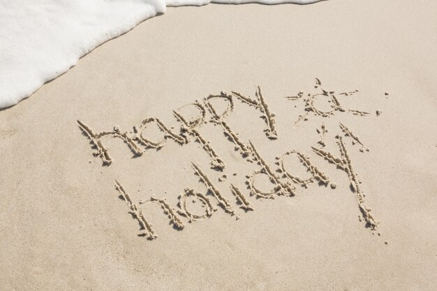 Happy holiday written on sand