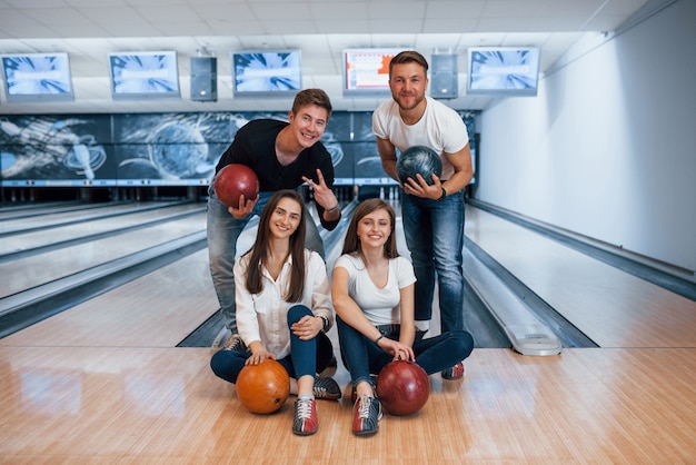 Happy holidays. Young cheerful friends have fun in bowling club at their weekends