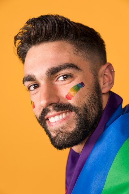 LGBTの虹色の旗で覆われて幸せな同性愛者の男