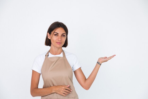 Happy housewife in apron isolated on white  hold hand right with empty space