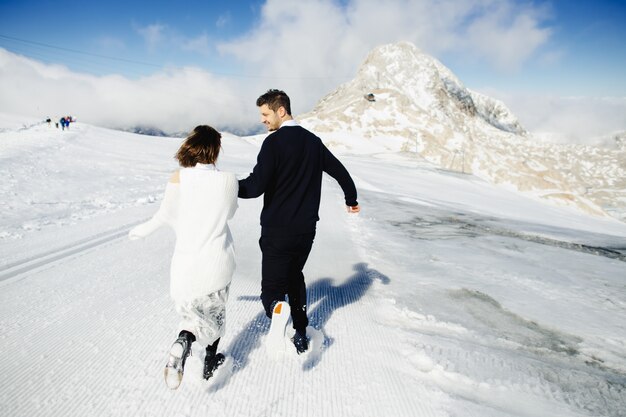 幸せな夫と妻は雪の中でどこかを走っています