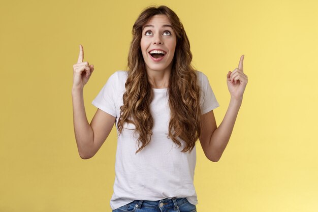 Happy impressed attractive girl long curly haircut drop jaw amused smiling surprised delighted look ...