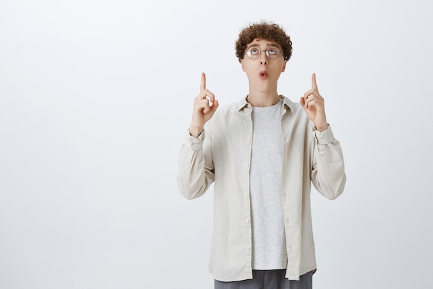 Happy impressed teenage guy posing against the white wall