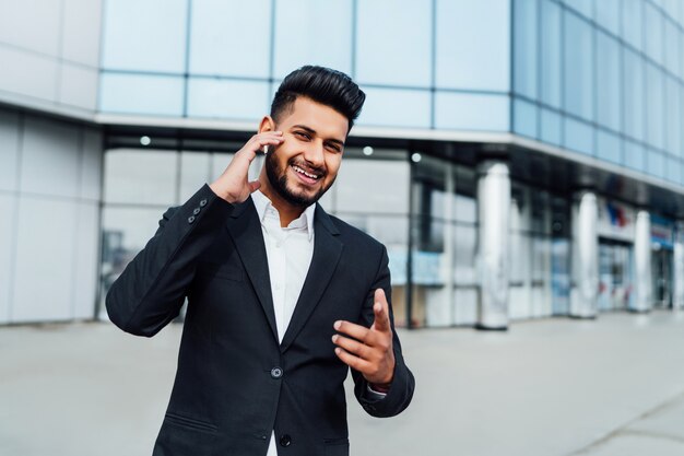Счастливый индийский бизнесмен перед современным офисным центром