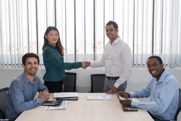 Happy Indian and Chinese partners shaking hands at business meeting 