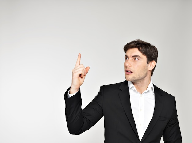 Happy inspiration businessman points his finger up in black suit