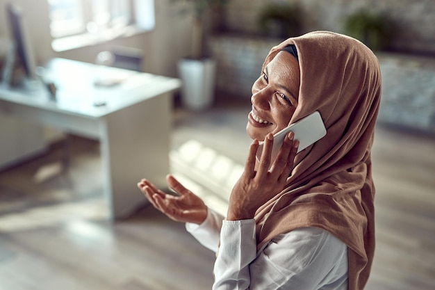 Счастливая исламская деловая женщина звонит по телефону во время работы в офисе