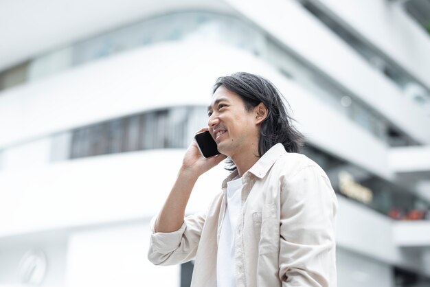 彼のスマートフォンで話している幸せな日本人男性