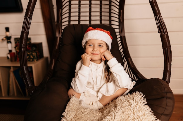 Happy joyful little girl wearing santa costume posing at home and waiting for christmas presents