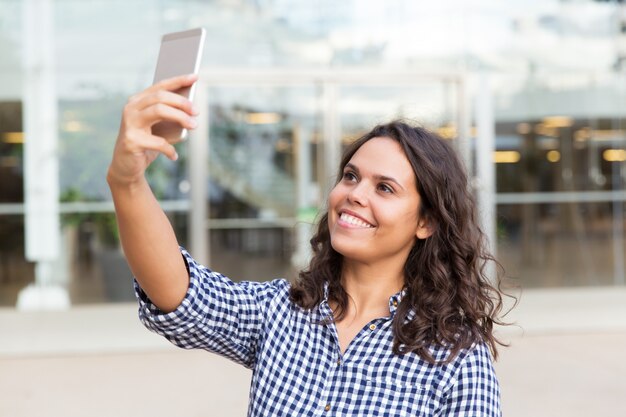 Selfieを取ってスマートフォンで幸せなうれしそうな女性