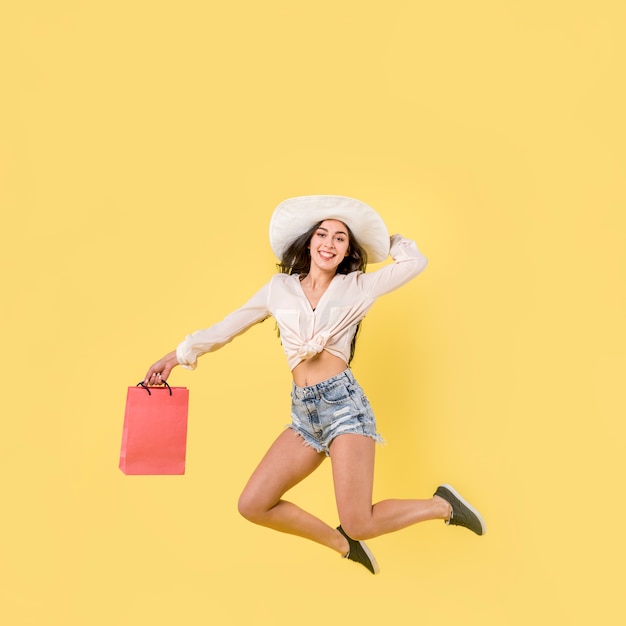 Free photo happy jumping woman with red paper bag