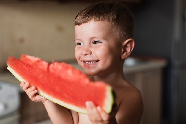 Happy kid holding a slice of watermelon