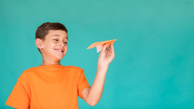 Bambino felice con l'aeroplano di carta con lo spazio della copia