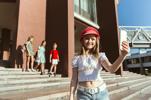 Happy kids playing at city's street in sunny summer's day in front of modern building