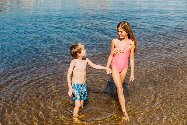 Happy kids standing in water on beach