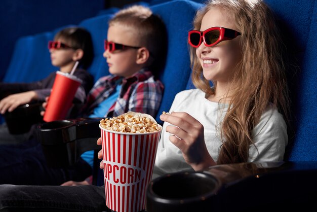 Счастливые дети смотрят фильм в 3d очки в кино.