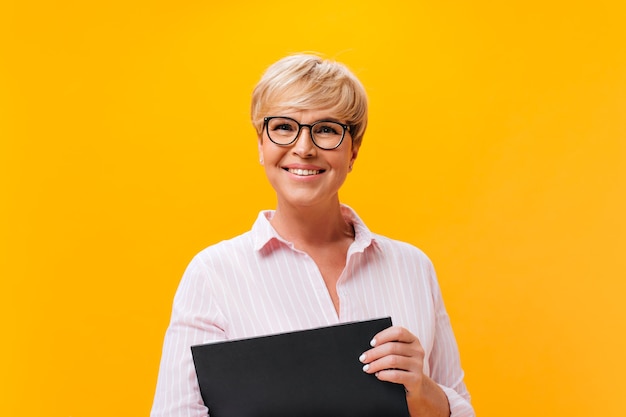 Free photo happy lady in eyeglasses and pink shirt smiling on orange background