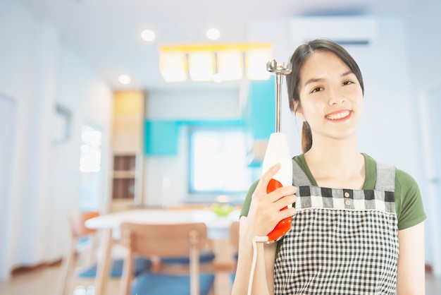 Happy lady holding kitchen stuff over copy space background 