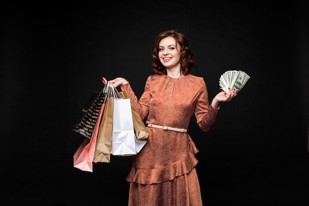 Happy lady with shopping bags and money in hands.