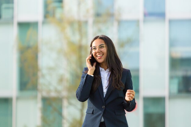 Happy Latin businesswoman talking on cellphone