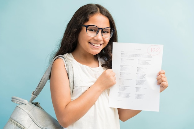 Happy Latin girl showing her perfect test results while making eye contact in studio