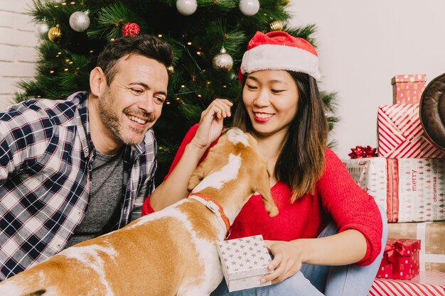 Happy laughing couple celebrating christmas with dog